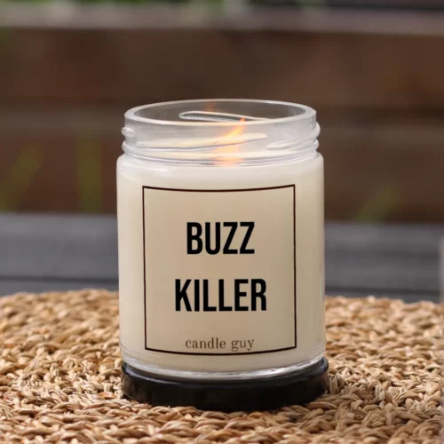 Brennende Anti-Mücken-Kerze mit dem Spruch „Buzz Killer“ im weißen Glas in gemütlicher Umgebung