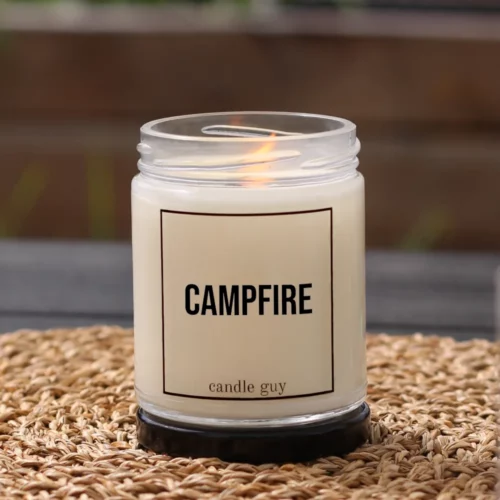 Brennende Anti-Mücken-Kerze mit dem Spruch „Campfire“ im weißen Glas in gemütlicher Umgebung