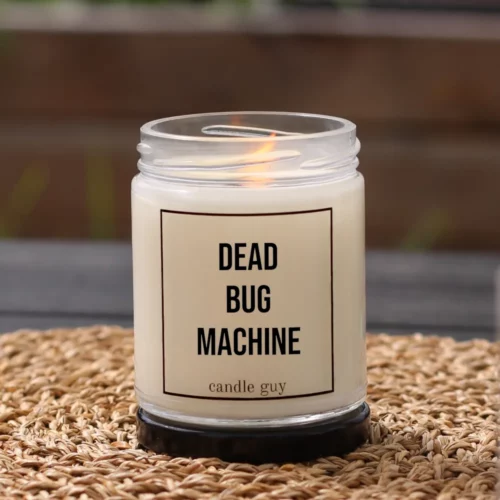 Brennende Anti-Mücken-Kerze mit dem Spruch „Dead Bug Machine“ im weißen Glas in gemütlicher Umgebung